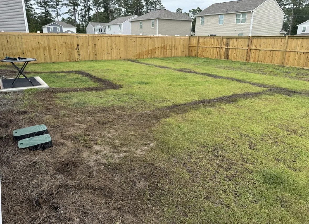 Backyard with trenched irrigation lines and valve boxes set before sod installation