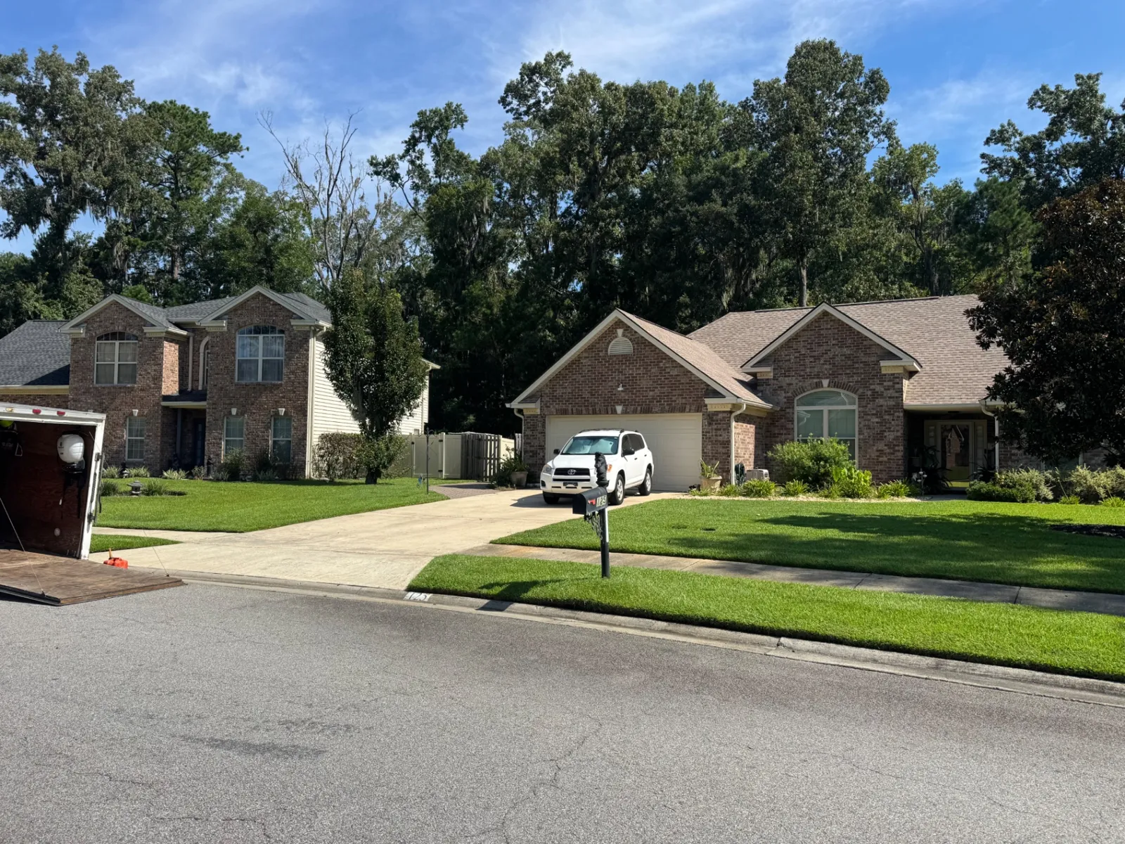 Crisp edged front lawn and driveway at two brick homes on a maintenance route